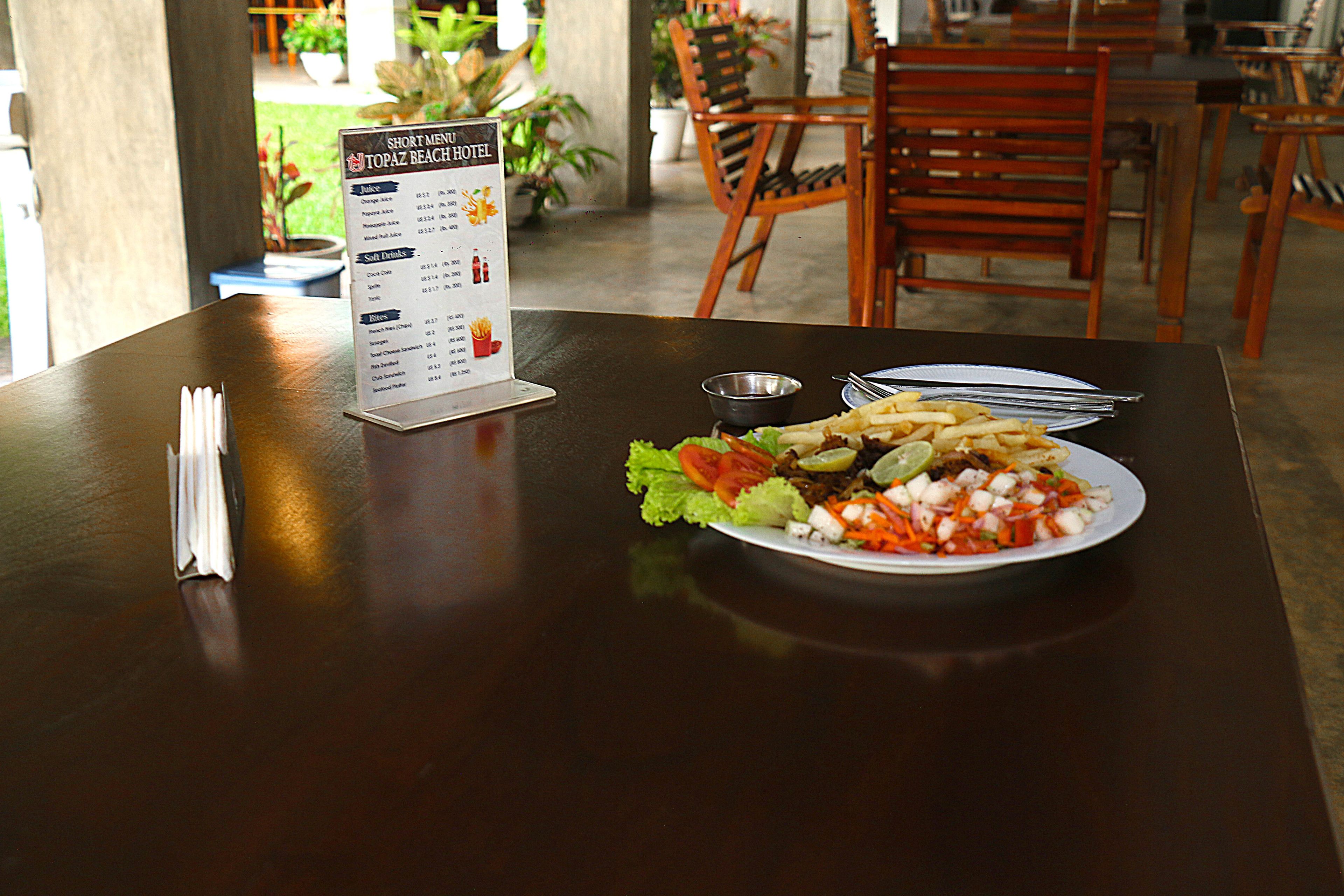 A table with a menu, a plate of food, and a small bowl of sauce.