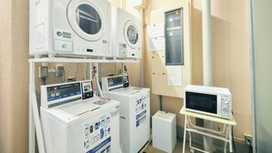 A laundry facility with multiple washing machines and a microwave. - Urbain Tokyo Haneda Kamata (Tokyo)