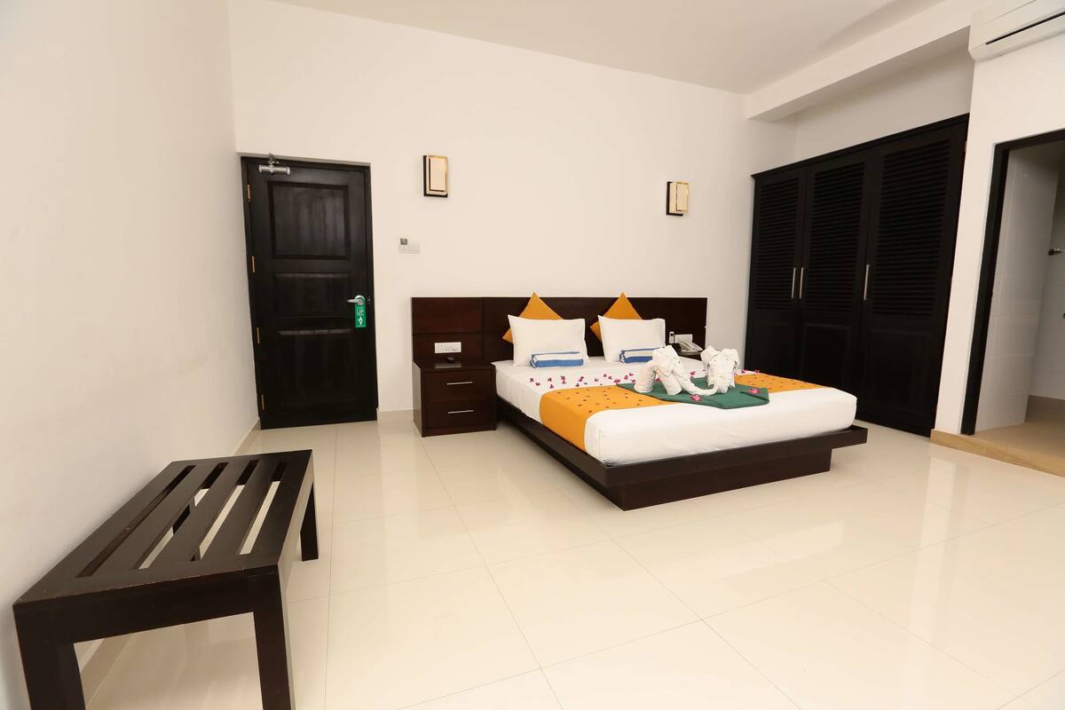 A hotel room with a bed, bedside tables, a bench, and a wardrobe.