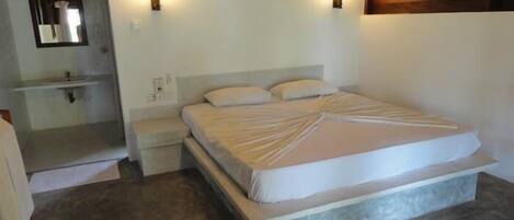 Un dormitorio con una cama grande, mesitas de noche, un espejo y una lámpara de pared.