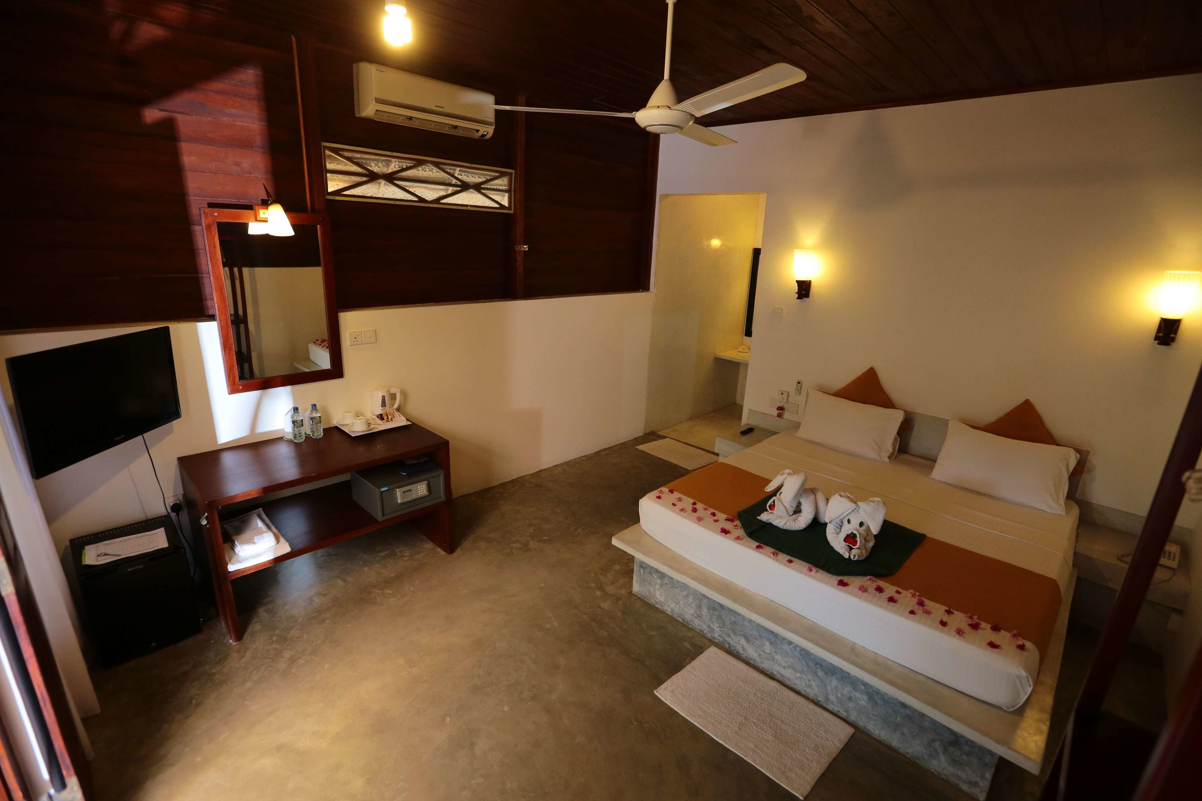 A bedroom with a bed, bedside table, mirror, and ceiling fan.