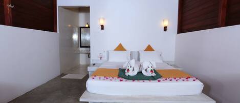 A bedroom with a bed, pillows, bedside tables, and wall-mounted lights.