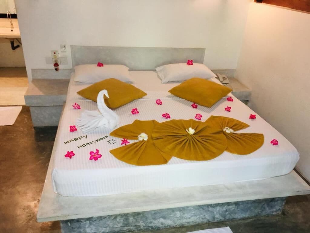 A bed with a white mattress, two pillows, and decorative swan-shaped towels.