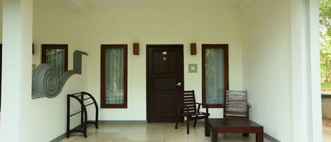 A clean, modern entrance with a dark wooden door, two wooden chairs, a bench, and a small table.