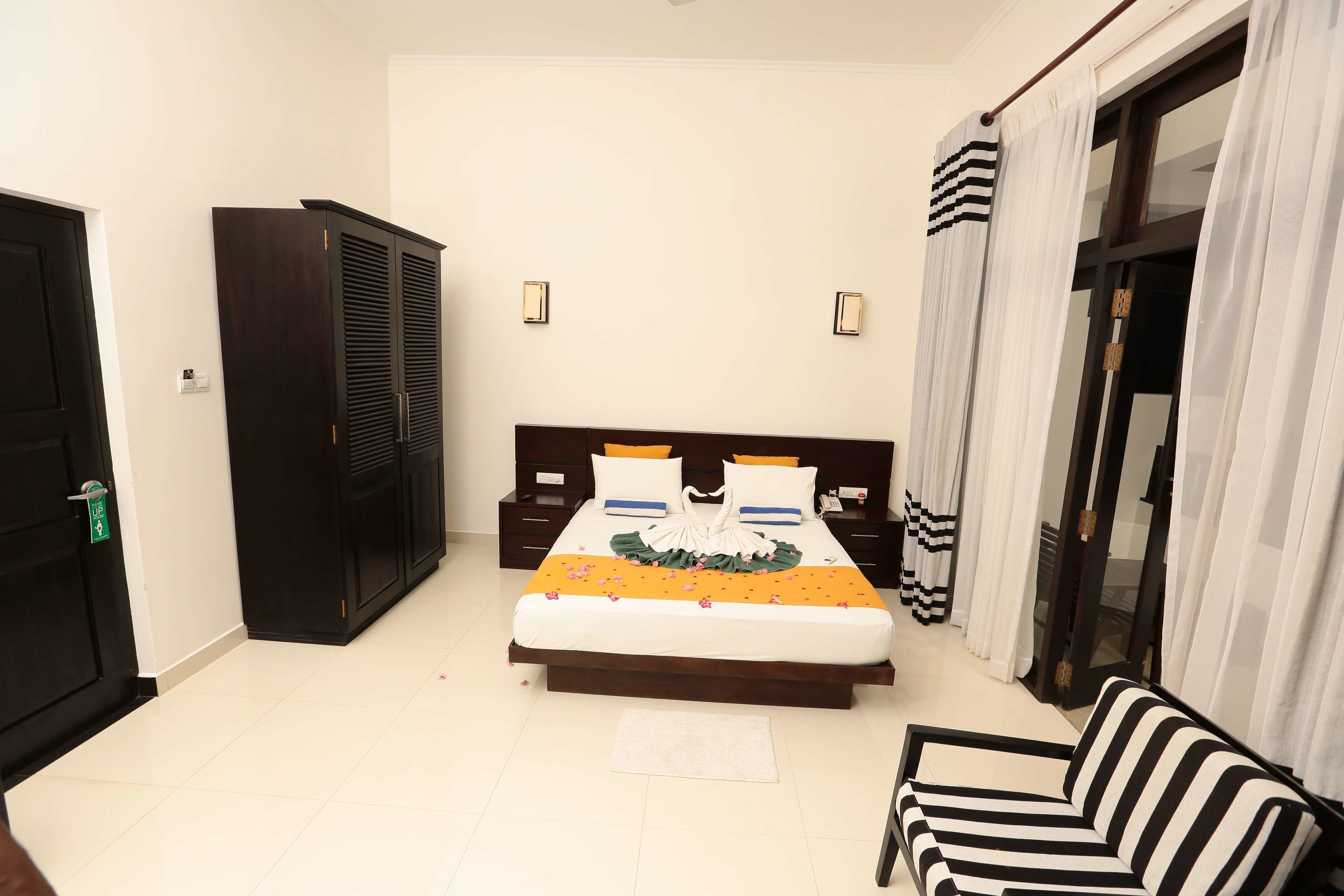 A bedroom with a bed, a wardrobe, a sofa, and a sliding glass door.