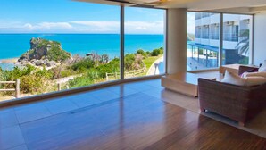 A spacious room with a large window overlooking a beach and ocean. - Hotel Hamahigashima Resort (Uruma)