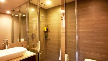 A modern bathroom with a glass-enclosed shower, a white sink, and a toilet.
