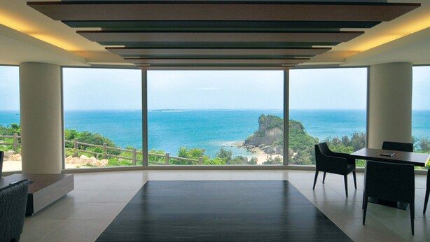 A modern room with a large window overlooking a coastal landscape. - Hotel Hamahigashima Resort (Uruma)