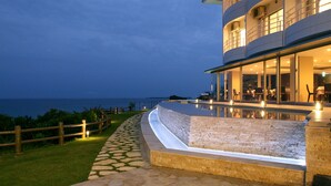 A modern building with a pool, outdoor seating, and a view of the sea. - Hotel Hamahigashima Resort (Uruma)