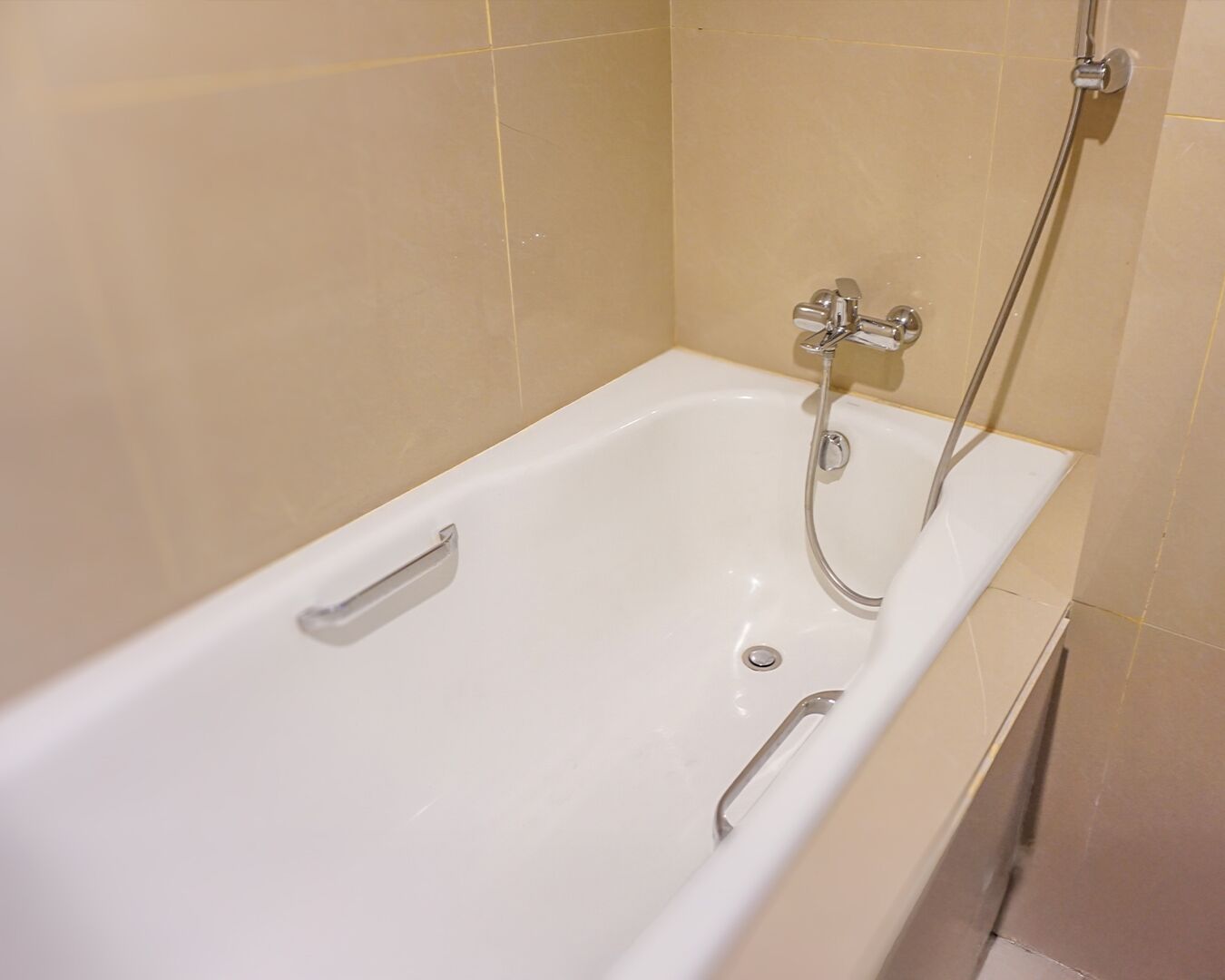 A white bathtub with a handheld showerhead and a fixed faucet.