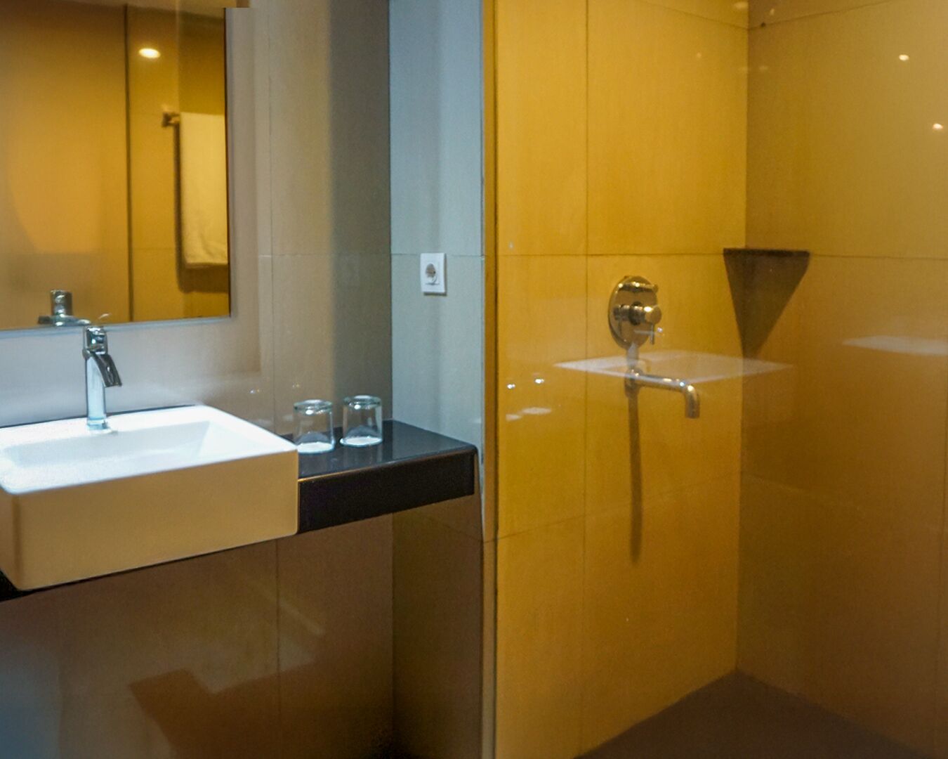Un bagno moderno con un lavandino bianco, barattoli di vetro e cabina doccia in vetro.