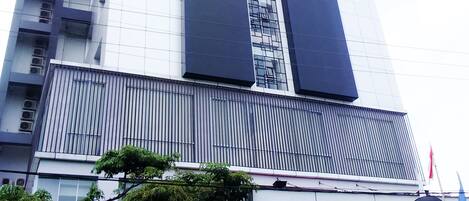A modern hotel building with a prominent vertical design, large windows, and a sign indicating it is a hotel.
