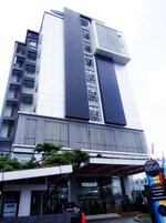 A modern hotel building with a prominent vertical design, large windows, and a sign indicating it is a hotel.