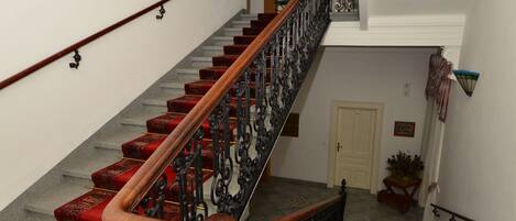 A staircase with red carpeted steps and ornate black railings.