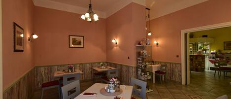 A dining area with a table set for four, chairs, a chandelier, and wall-mounted lights.