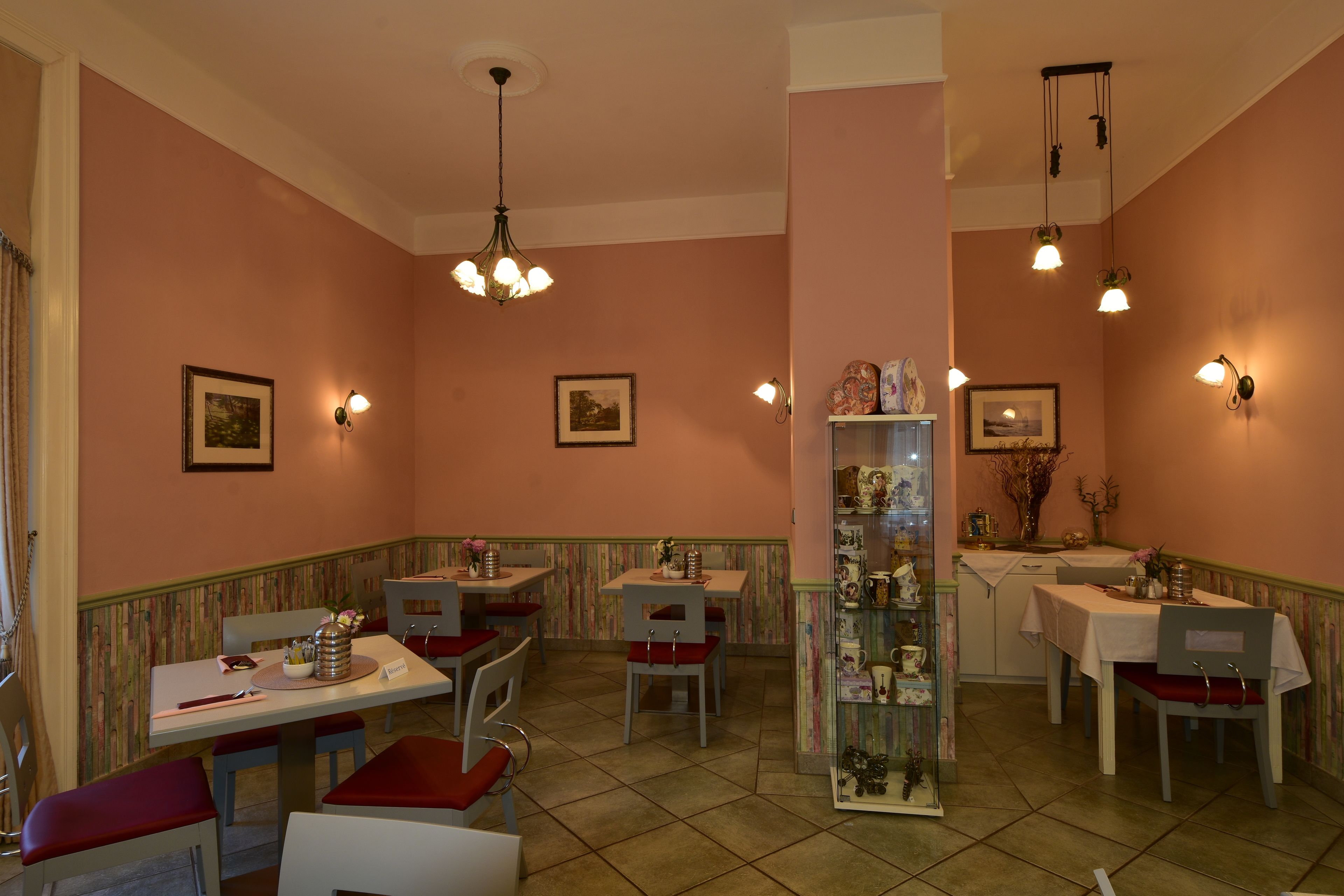 A dining area with multiple tables and chairs, a central decorative column, and wall-mounted light fixtures.