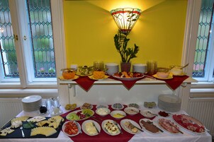 A buffet table with various food items and utensils, set against a yellow wall with a decorative lamp.