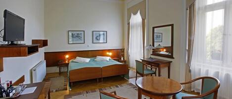 Une chambre d’hôtel comprenant un lit, un bureau avec un ordinateur, une table ronde et deux chaises.