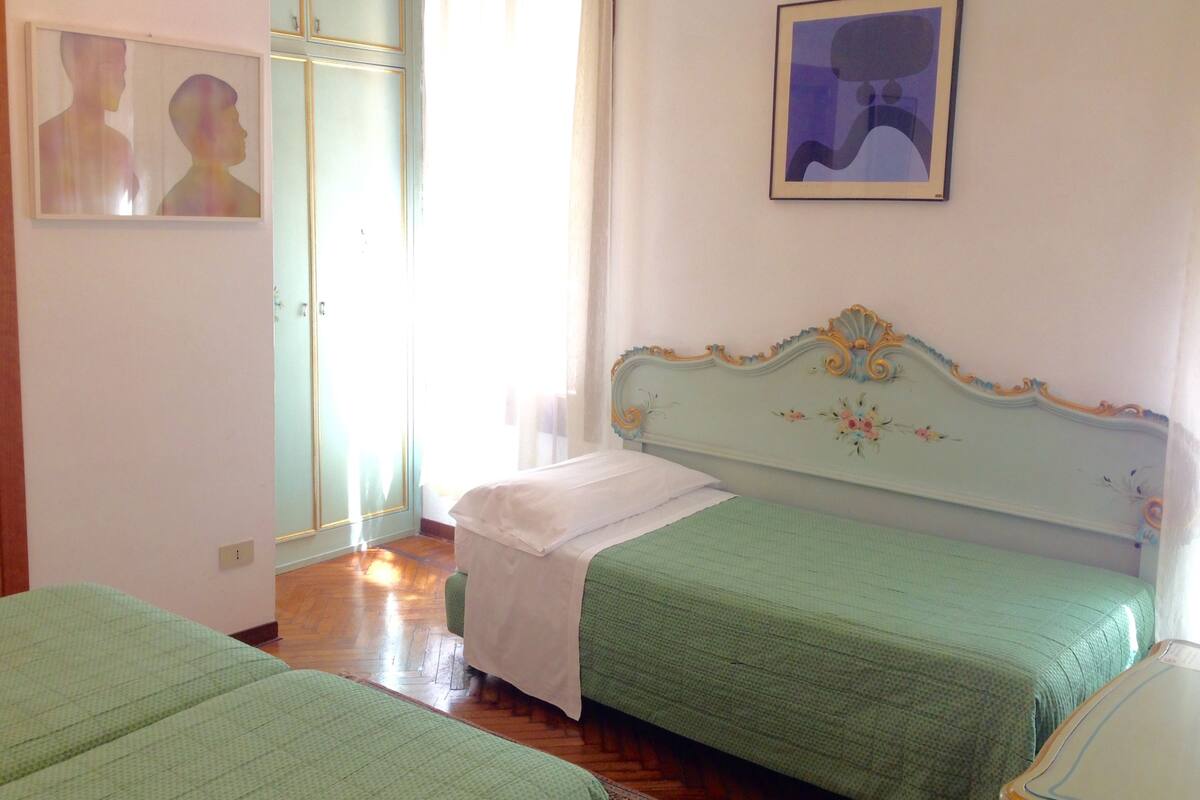 A bedroom with two single beds, a wardrobe, and a framed picture on the wall.