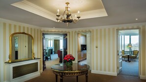 A room with a chandelier, a round table with a vase of red flowers, and a large mirror. - Cheval Thorney Court at Hyde Park (London)