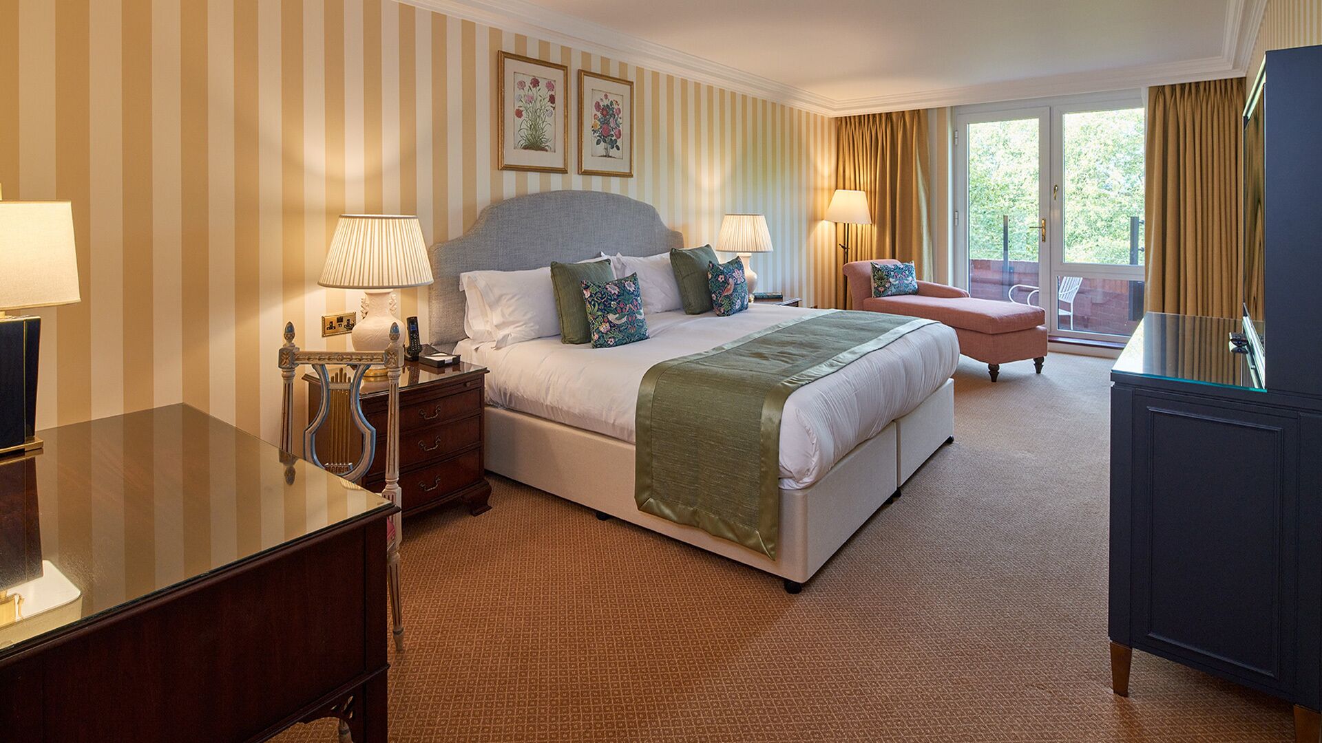 A hotel room with a large bed, bedside lamps, a dresser, a desk, and a chair.