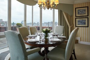 A dining room with a round table set for six, large windows, and a view of the city. - Cheval Thorney Court at Hyde Park (London)