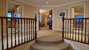 A staircase with a wooden railing leading to a dining area with a table and chairs. - Cheval Thorney Court at Hyde Park (London)