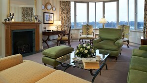 A spacious living room with a fireplace, comfortable seating, and large windows offering a city view. - Cheval Thorney Court at Hyde Park (London)