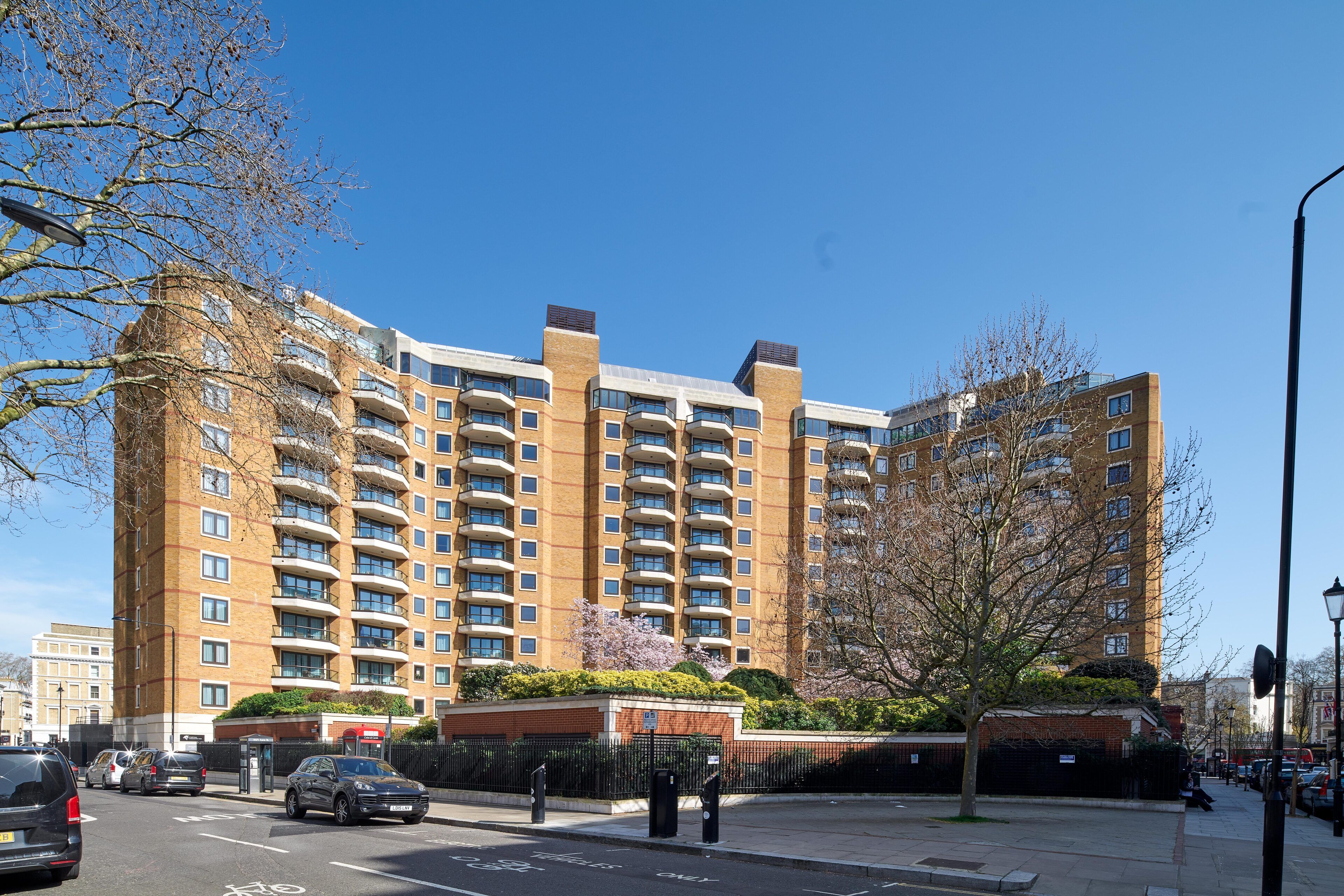 A multi-story hotel with a brick facade, balconies, and a gated entrance.
