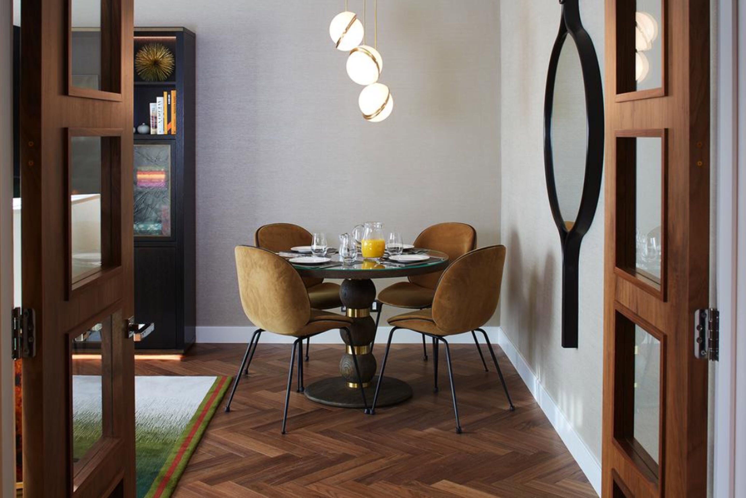 Un coin repas avec une table ronde, quatre chaises et une bibliothèque en arrière-plan.
