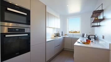 A modern kitchen with a built-in oven, a window with a city view, and a countertop with kitchen tools and fruits.