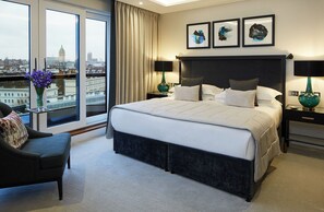 A modern hotel room with a large bed, a view of the city, and two framed artworks on the wall. - Cheval Gloucester Park at Kensington (London)
