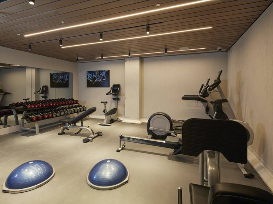 Un gimnasio con equipo de ejercicio, mancuernas y pelotas de entrenamiento.