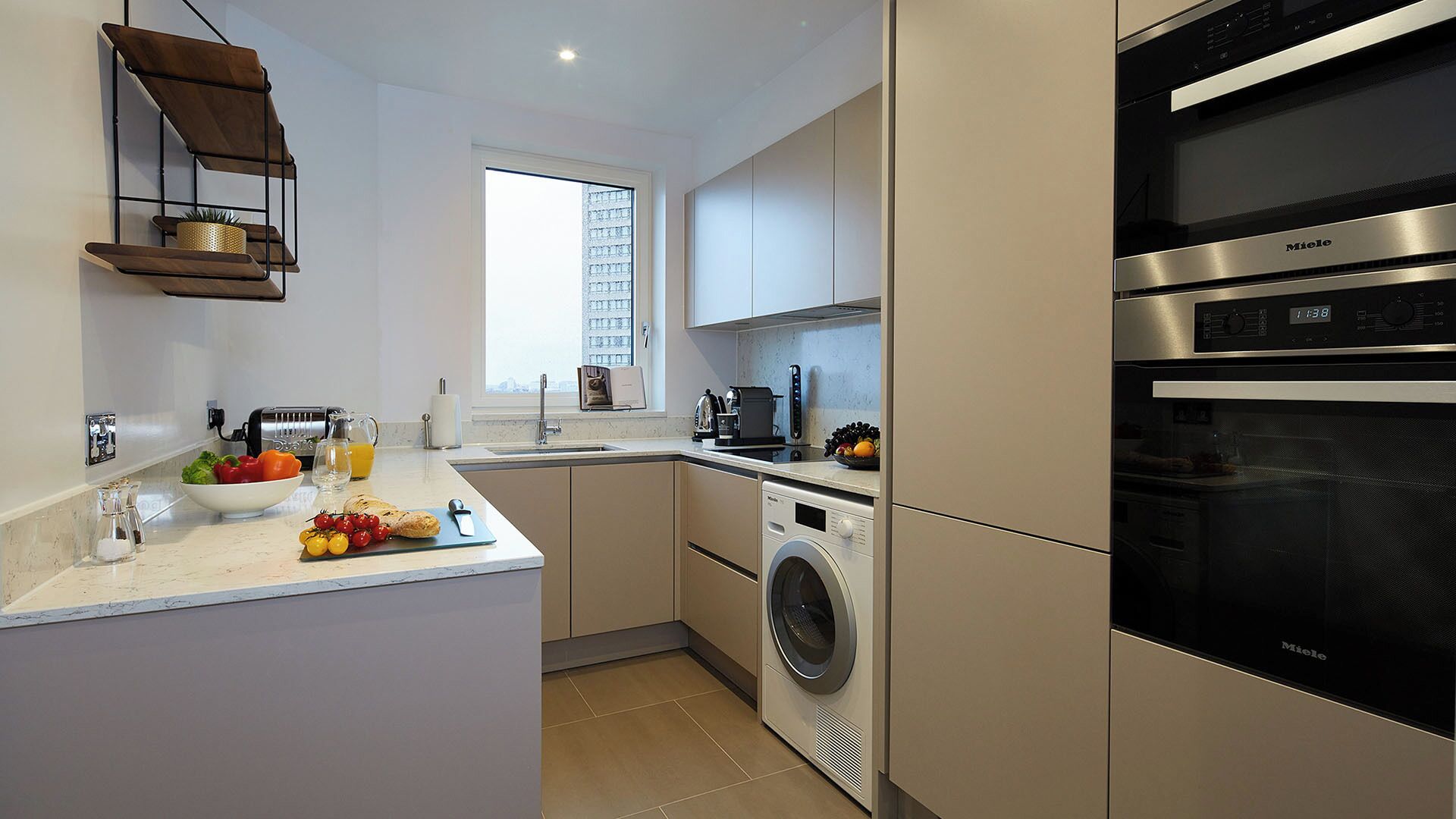 A modern kitchen with a built-in washing machine, a large oven, and a window with a city view.
