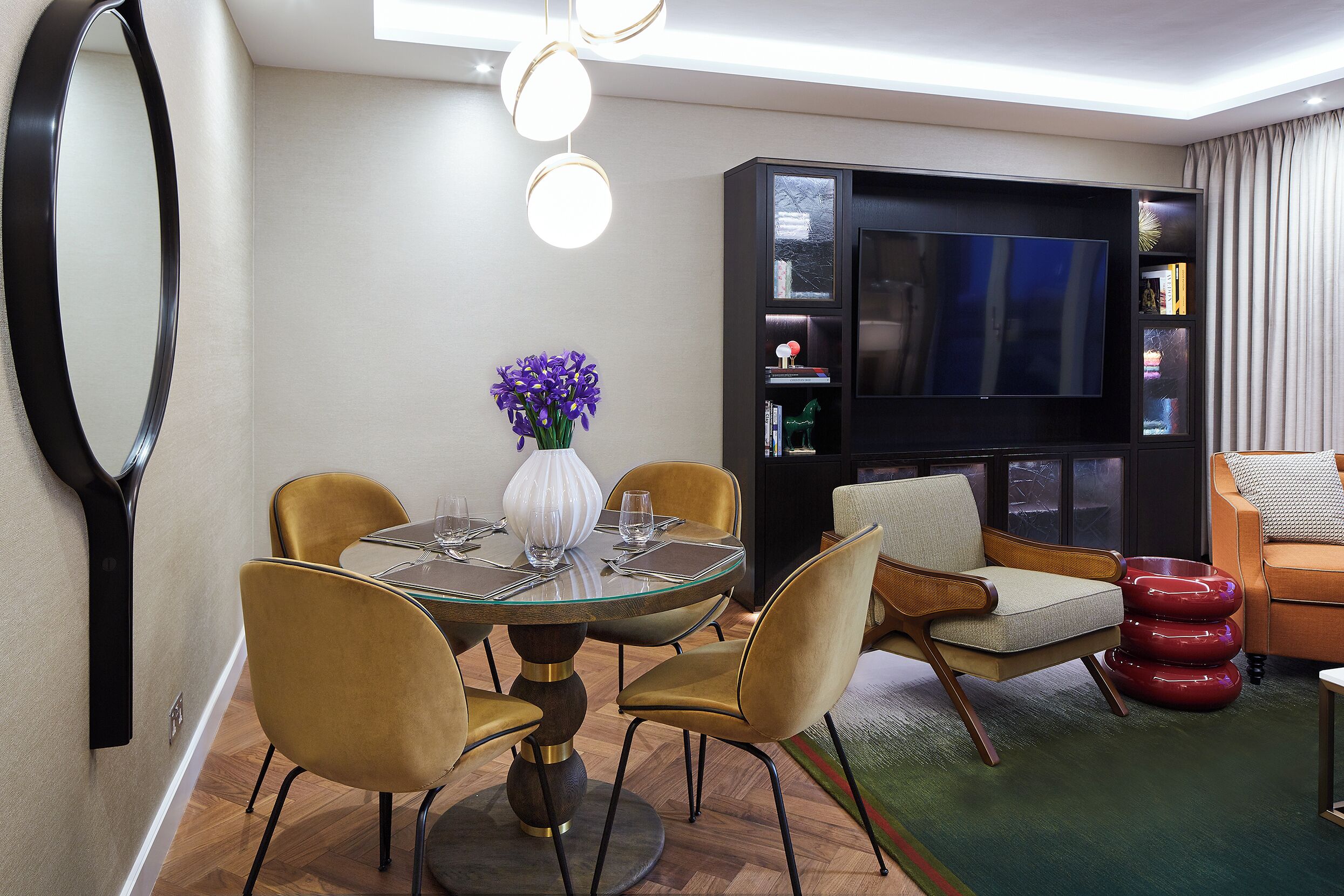 Una sala de estar moderna con una mesa de comedor redonda, sillas, un televisor y una estantería.