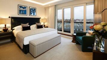 A hotel room with a large bed, a view of the city, and a balcony with flowers.