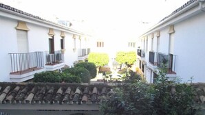 Un cortile con tetto in tegole, pareti bianche e balconi con ringhiere nere.