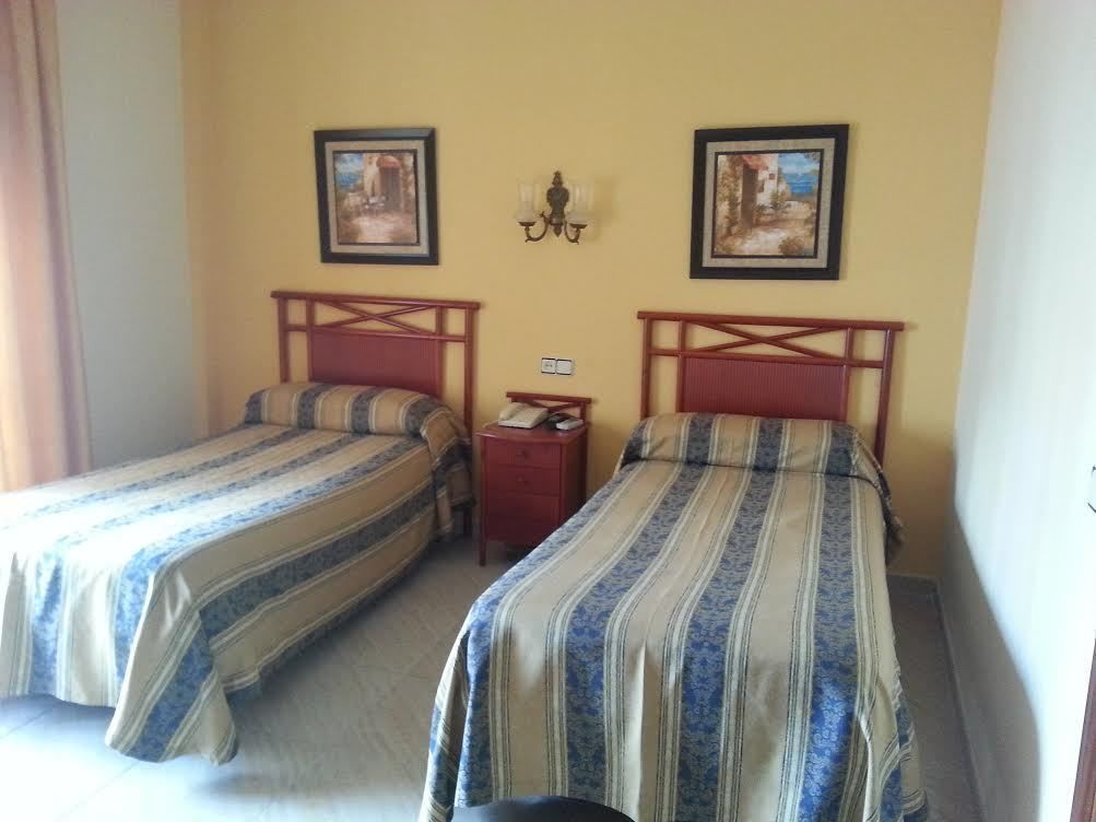 Une chambre avec deux lits, chacun doté de draps à rayures, d’une petite table de chevet et d’une lampe fixée au mur.