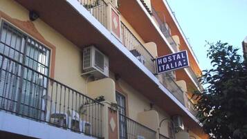 Un immeuble doté de balcons, de climatiseurs et d’une enseigne indiquant « HOSTAL ITALIA ».