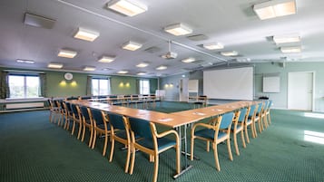 A conference room with a long table, chairs, a projector screen, and a whiteboard.