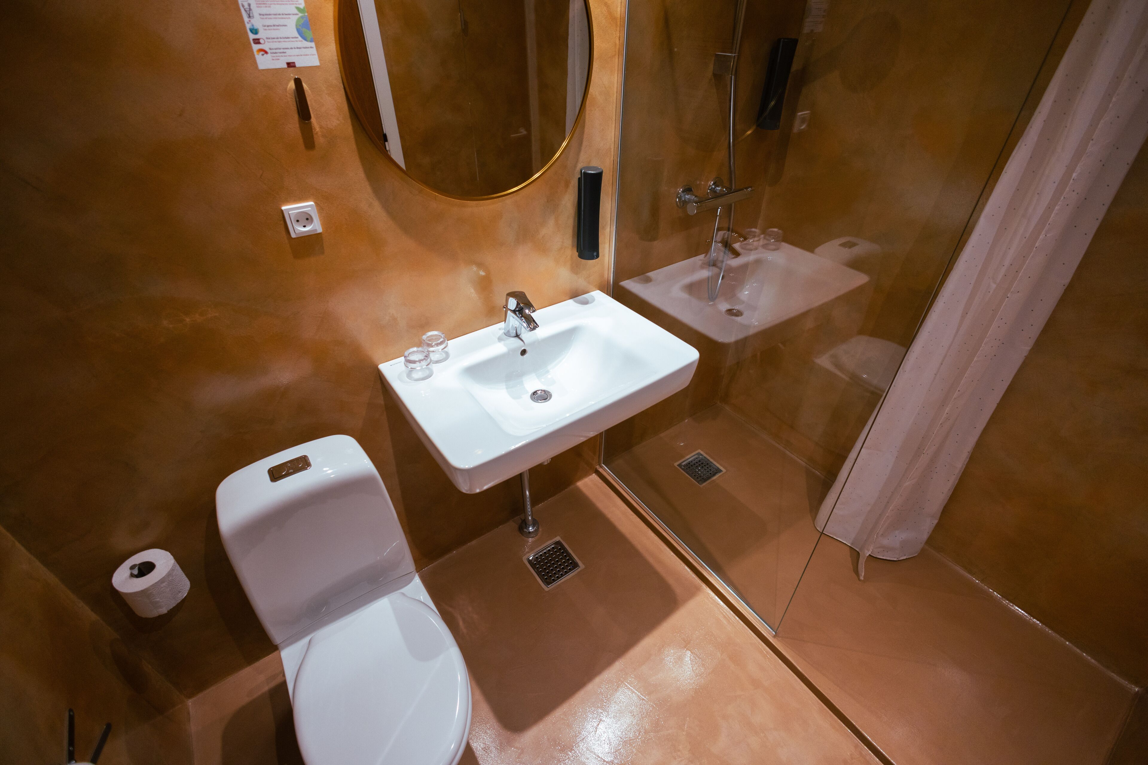 A bathroom with a white toilet, a white sink, and a shower area.