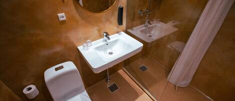 A bathroom with a white toilet, a white sink, and a shower area.