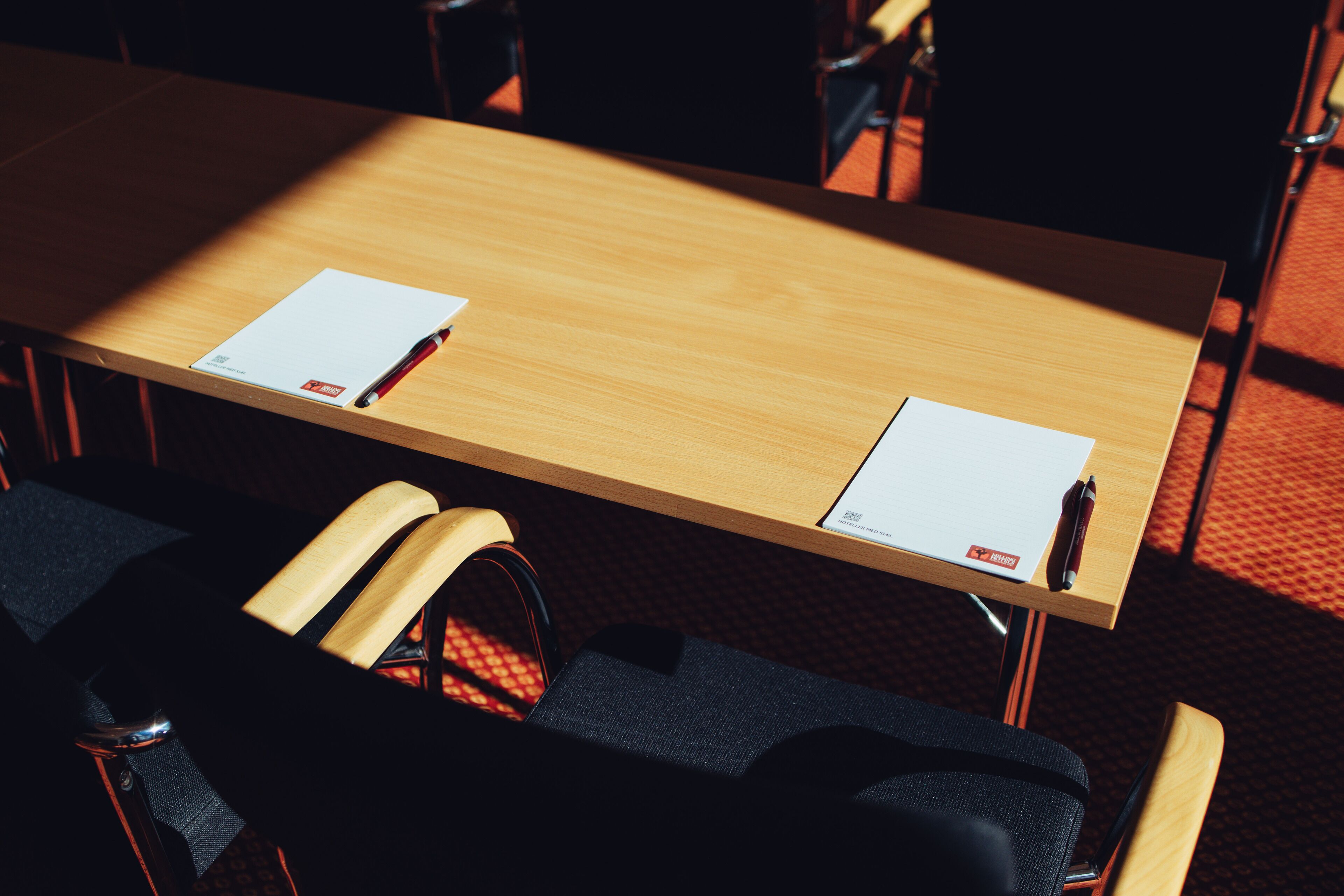 A conference table with two chairs, a black bag, and a pen on the table.