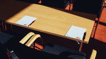 Un tavolo da conferenza con due sedie, una borsa nera e una penna sopra il tavolo.