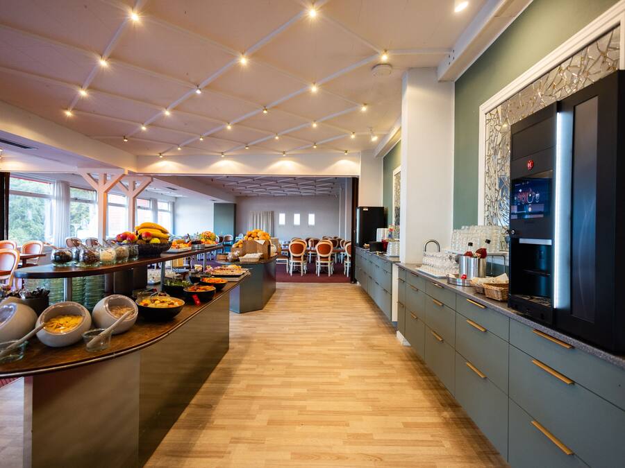 A modern kitchen with a central island, wooden flooring, and a large refrigerator.