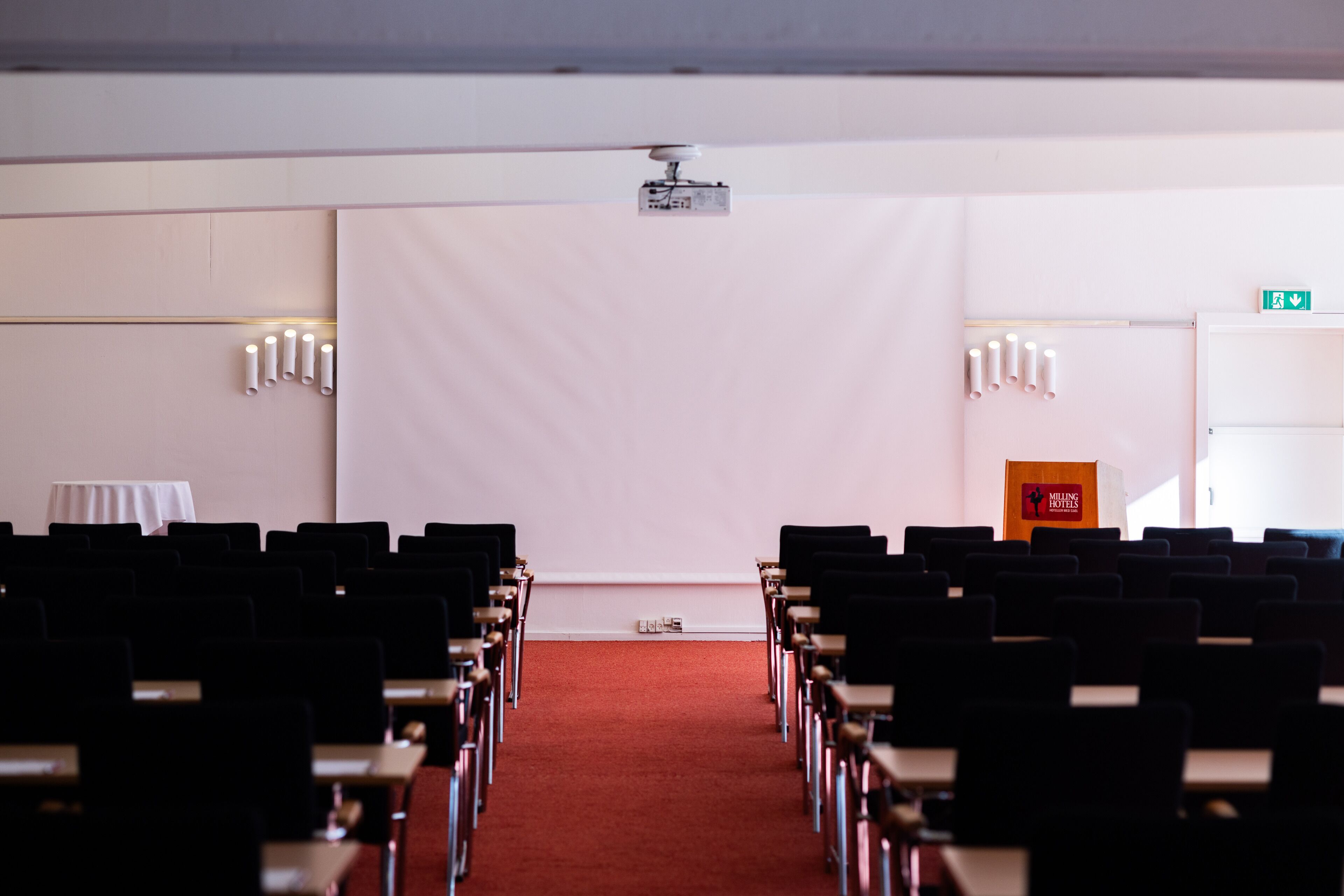 A conference room with rows of chairs, a projector, and a podium.