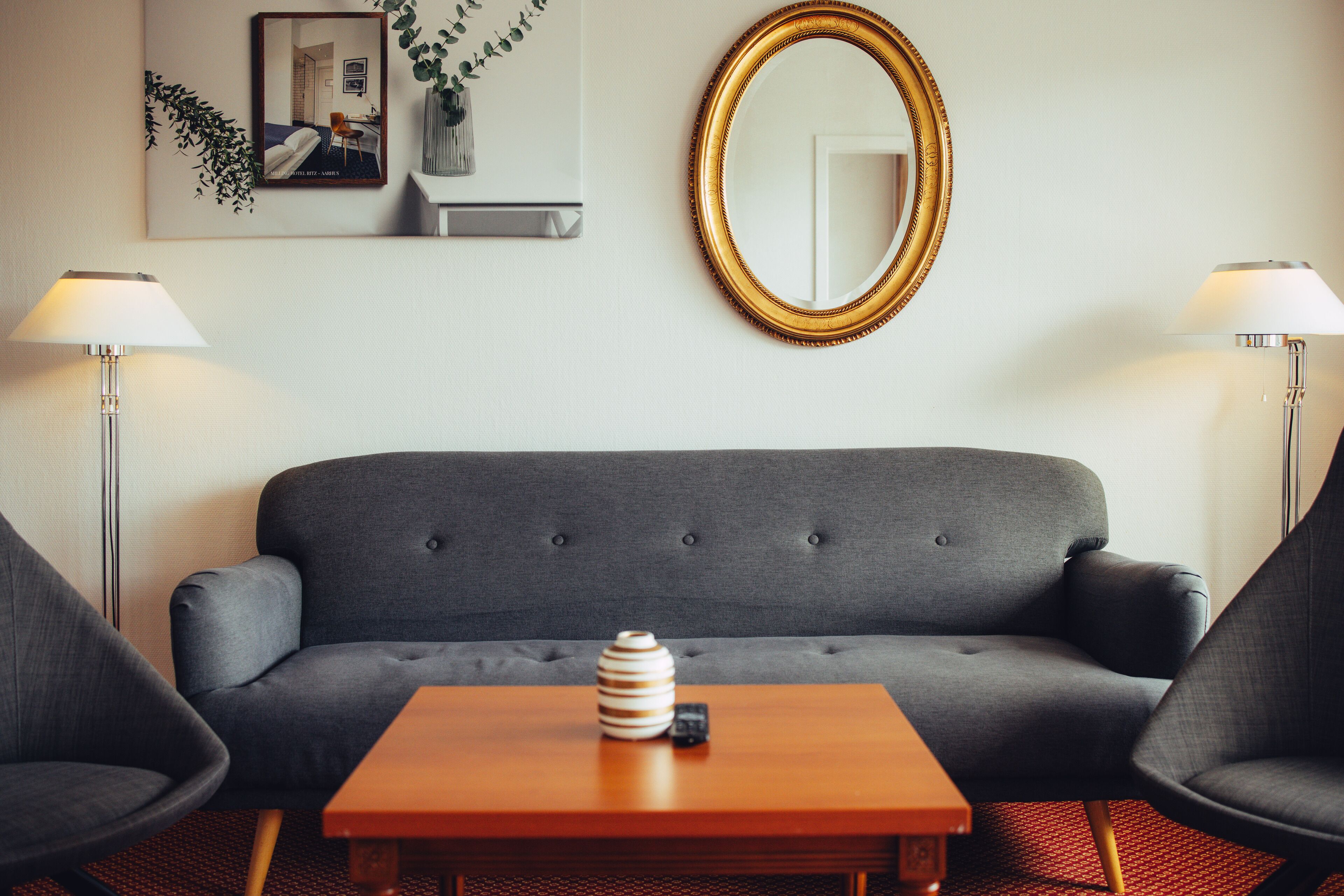 A modern living room with a grey sofa, a wooden coffee table, and two lamps.