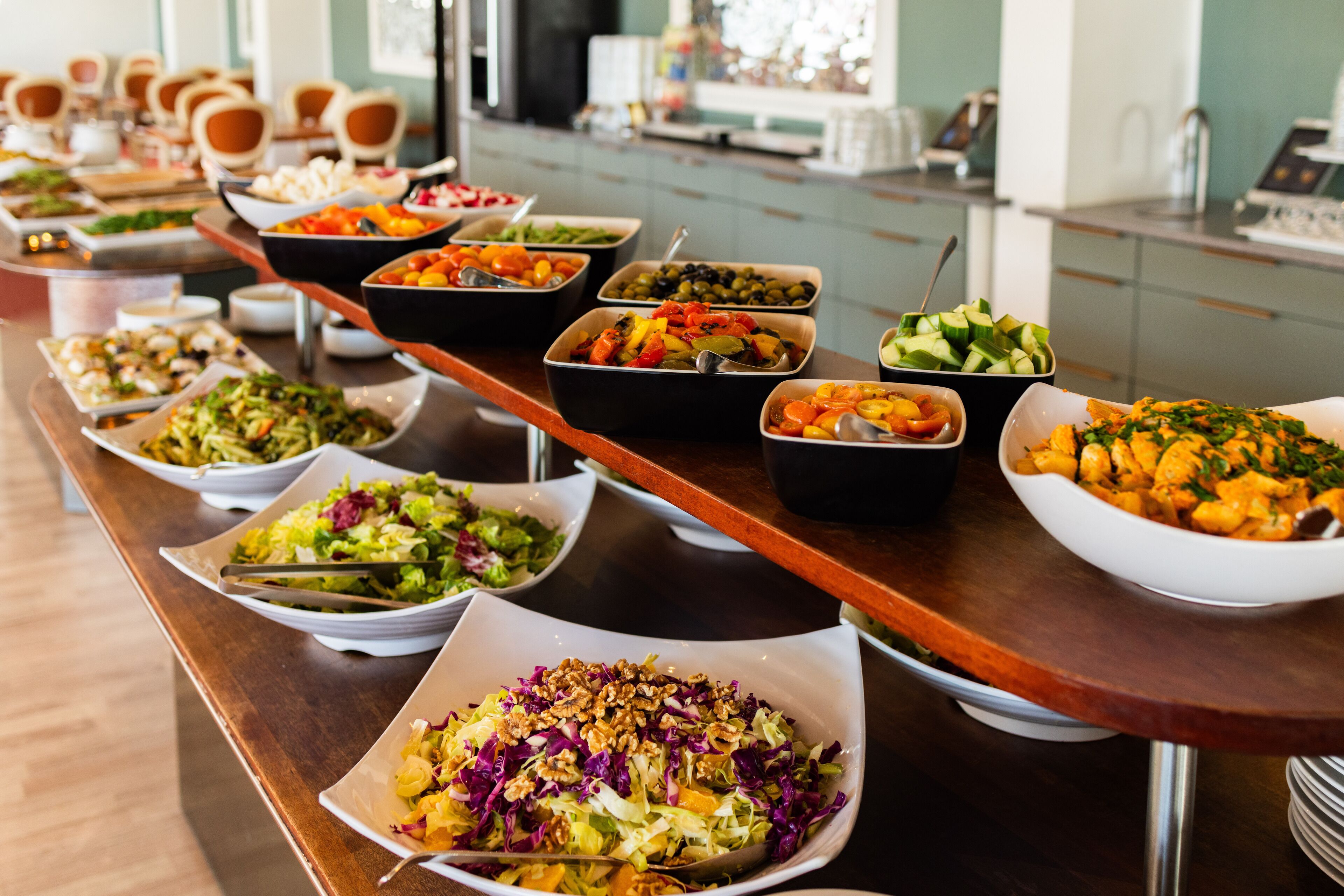 Una mesa de buffet con diversos platos, entre ellos ensaladas, verduras y otros alimentos.