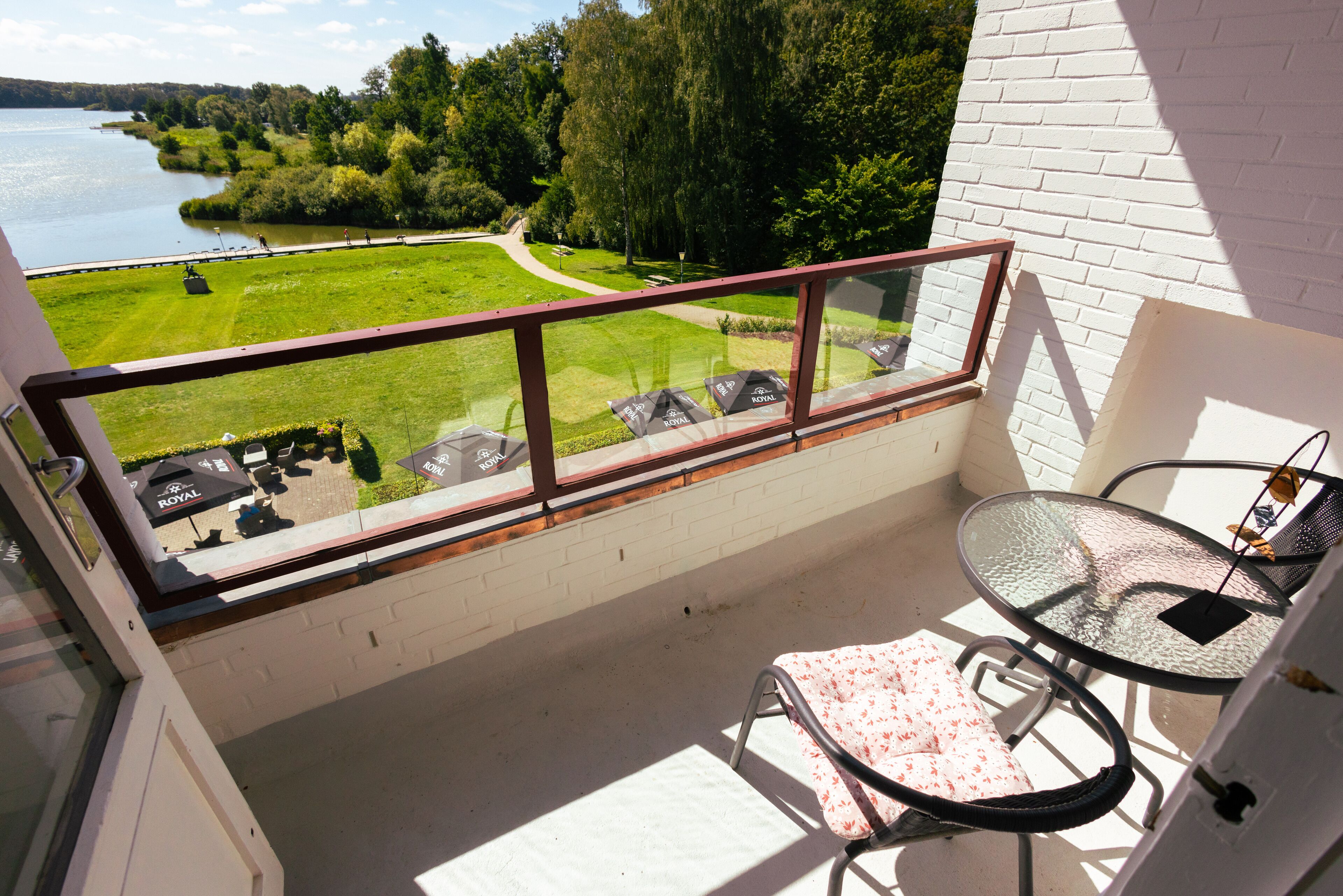 Un balcon doté d’une balustrade en verre, d’une table et d’une chaise.