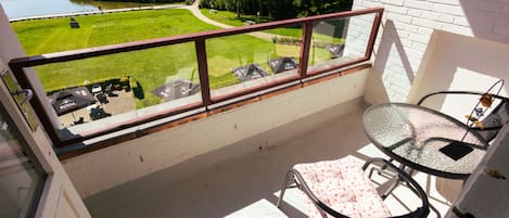 Un balcon doté d’une balustrade en verre, d’une table et d’une chaise.